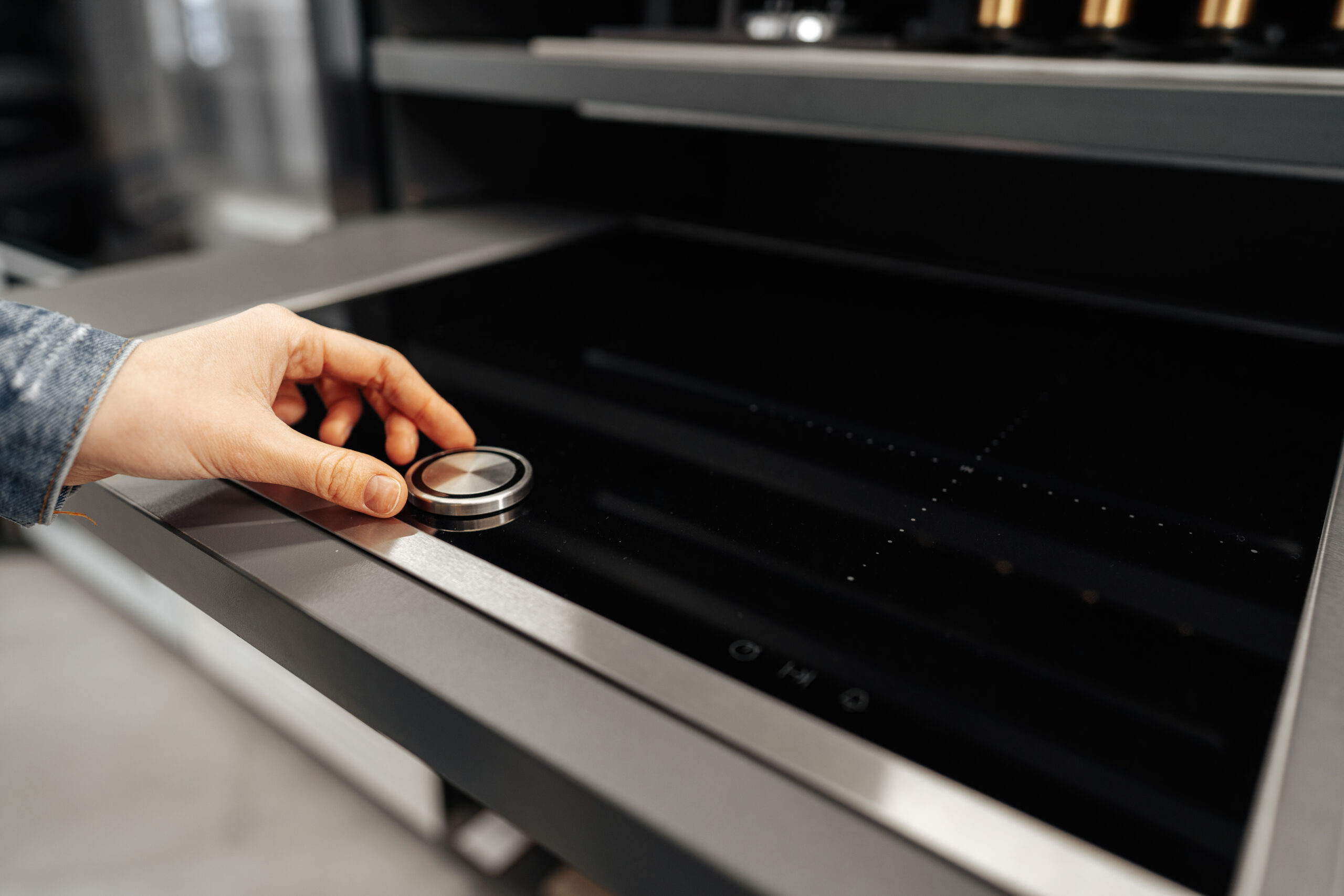 close up woman hand checking new stove hypermarket scaled